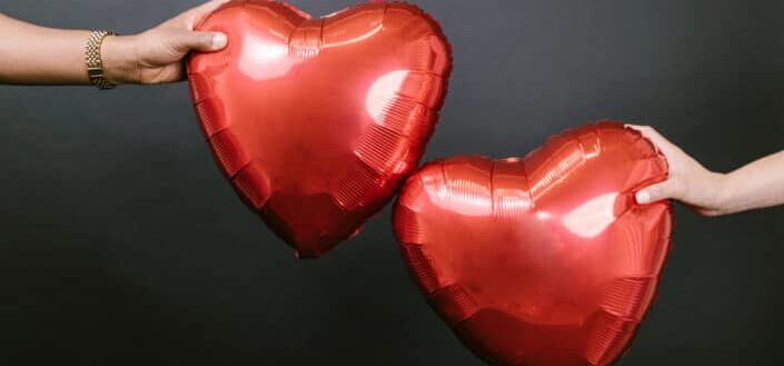 Two Red Heart Balloons Being Put Together