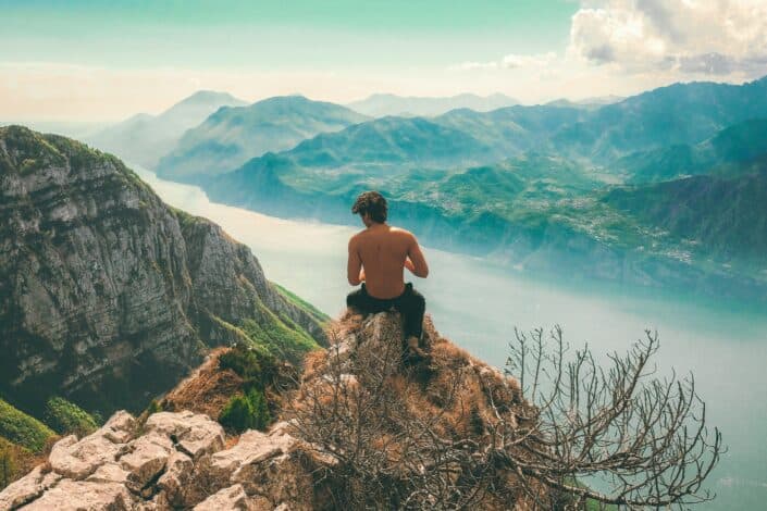 shirtless guy sitting on a mountain cliff