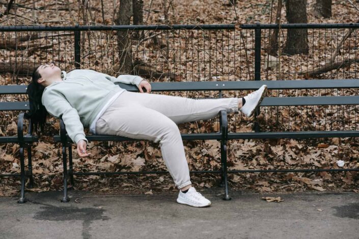 woman lazily lying on a park bench