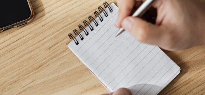 crop man writing on small notebook