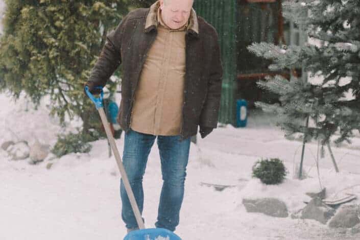 Old man shoveling snow deposits.