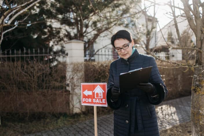 Woman holding contract for a house for sale.