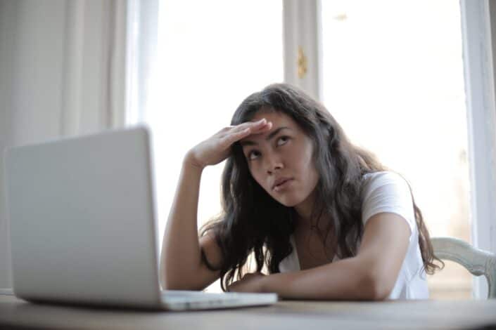 A woman on a deep thought in front of her computer