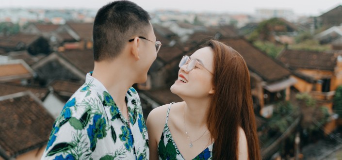 smiling asian couple on balcony under gray sky