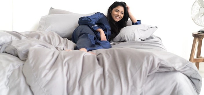 Happy woman laying comfortably at her bed.