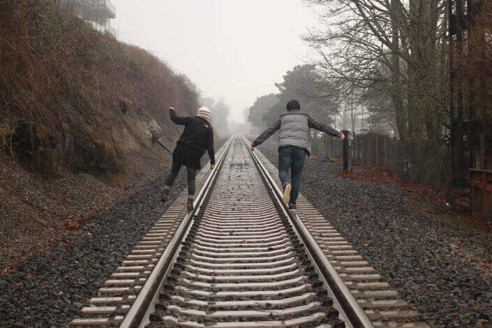 couple having fun trailing on the train rail.