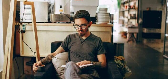 Man reading a book on a couch.