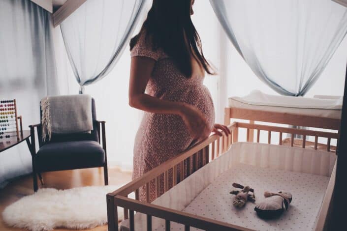 Pregnant woman standing by the crib