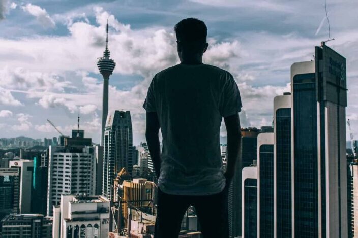 Man standing while facing concrete buildings