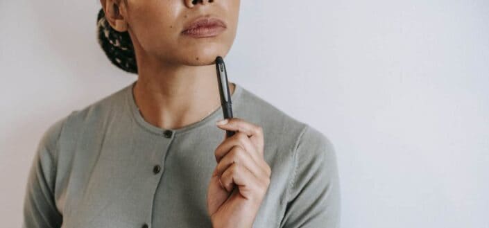 Woman holding pen to chin