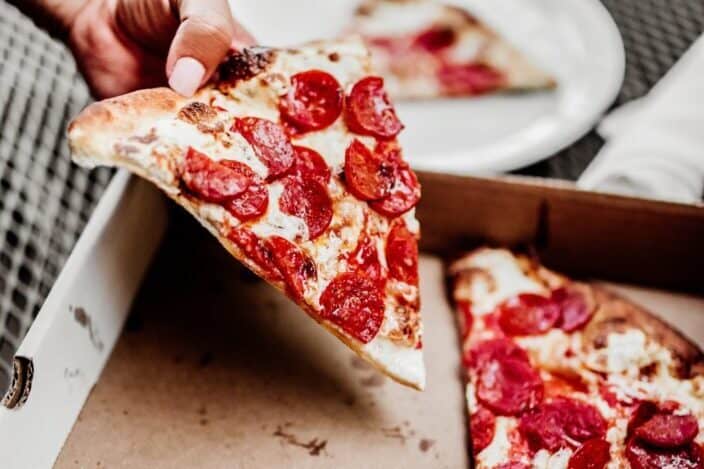 Guy holding a piece of pizza