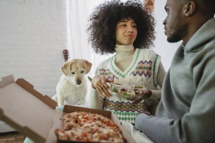 Couple eating pizza with their puppy