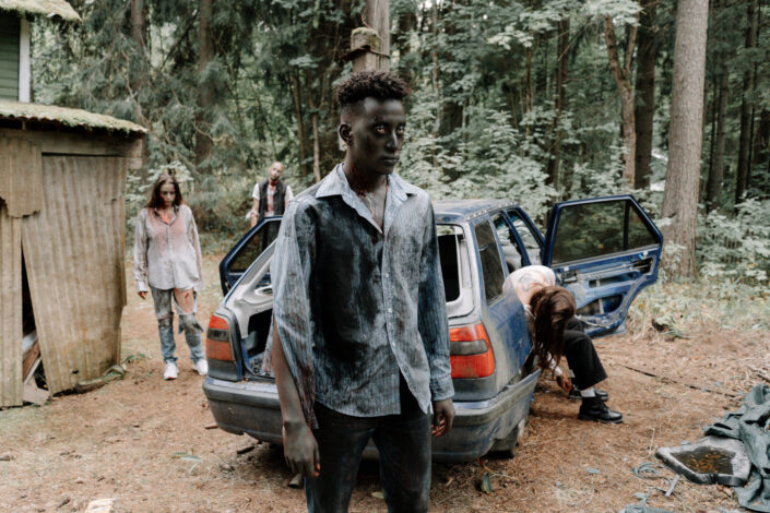 zombies walking by a ravaged car