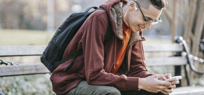 A guy smiling widely while reading a text.