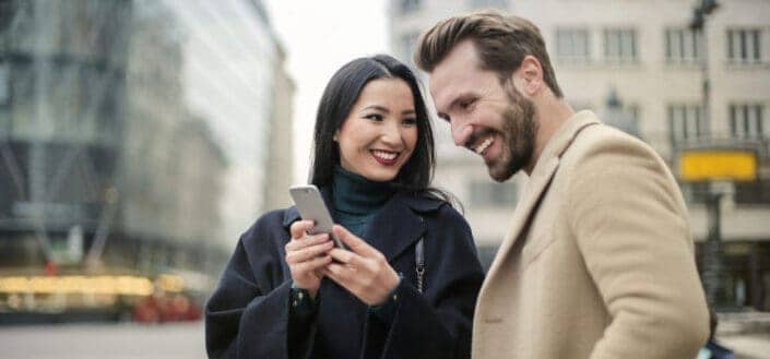 A woman excited to show what's on her phone to a guy.
