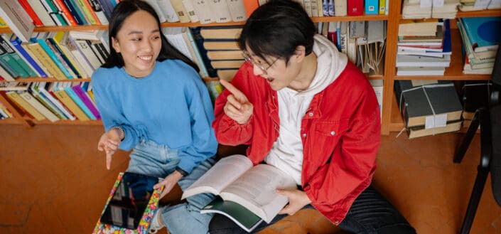 A teen couple having a playful banter in a library.