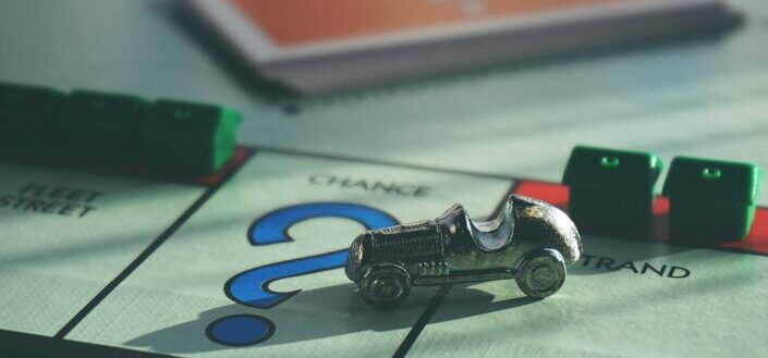 A vintage car place on top of a monopoly board game.