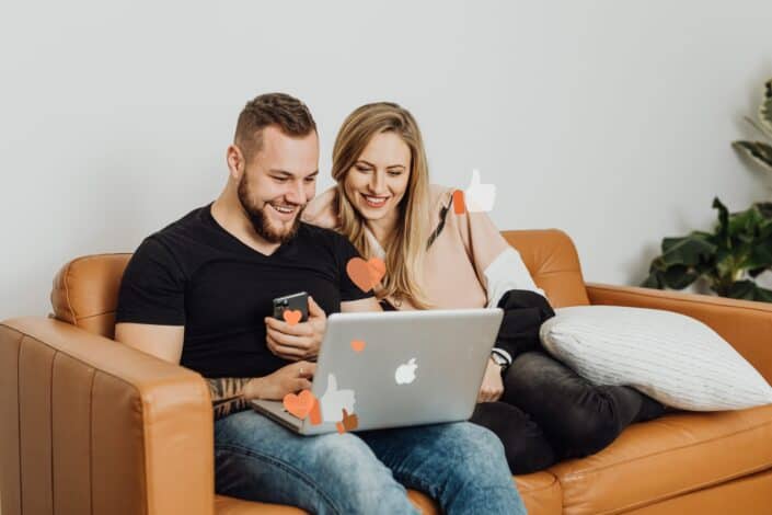 Happy couple looking at laptop while seated