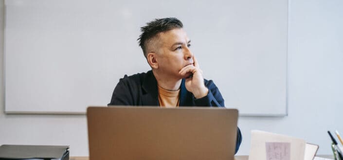 A mature man on a deep thought in front of his computer