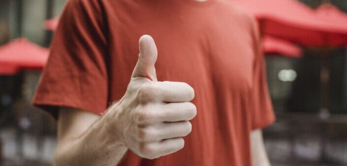 A man in a red shirt doing a thumbs up sign