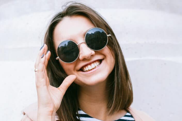A woman with a big smile wearing a black sunglasses