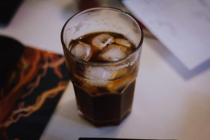 A glass of soda with ice cubes.
