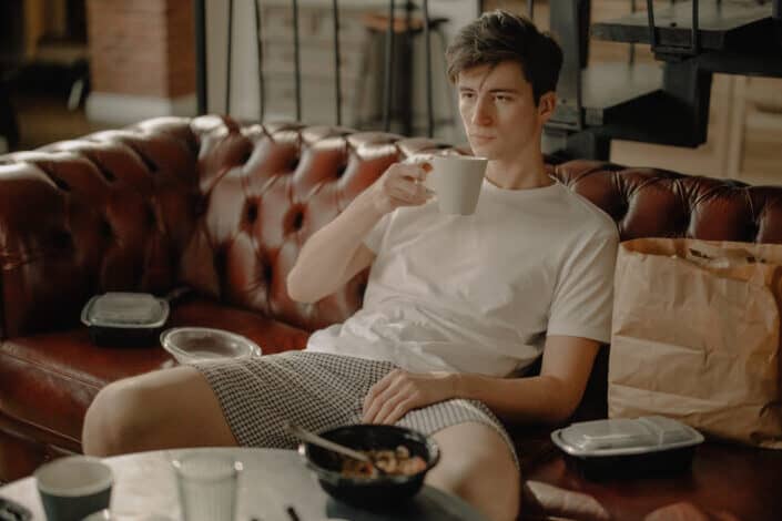 A guy having a breakfast on a couch.