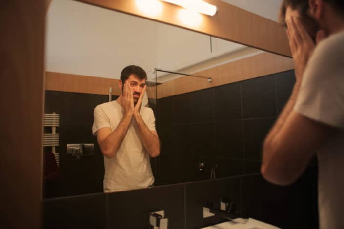 Man checking himself in the bathroom mirror.