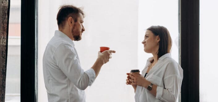 A Man and Woman Talking while holding coffee