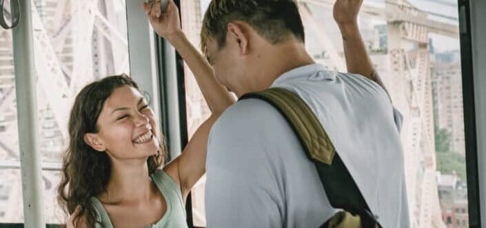 Cheerful couple riding cableway and laughing