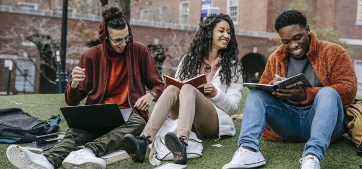three students with books sitting near university