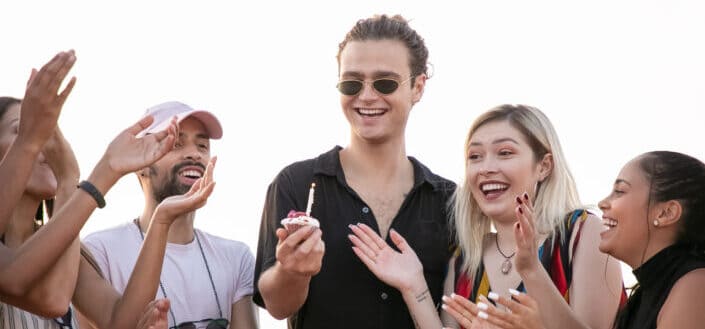 man with birthday cupcake having fun with friends