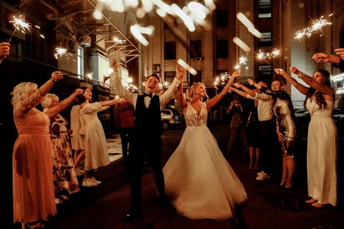 friends and newlywed couple celebrating wedding at night