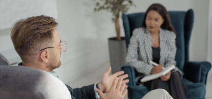 Man in Gray Sweater Sitting Beside Woman in Black and White Shirt