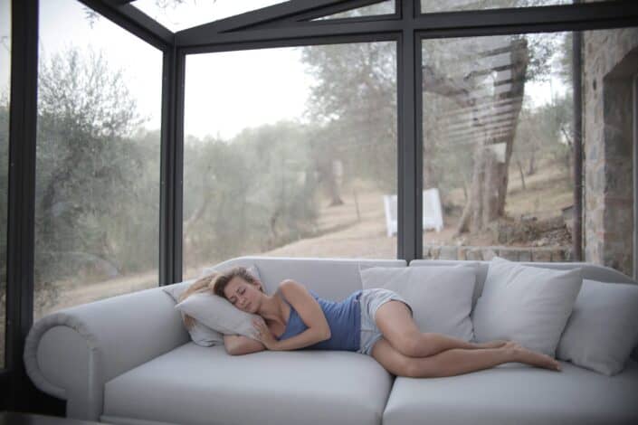 Woman Sleeping on Gray Couch Inside Glass Room