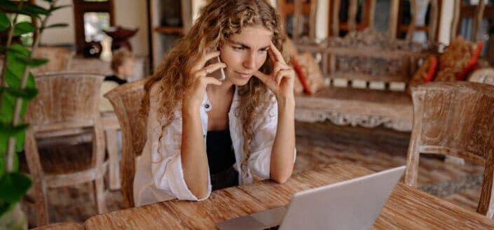 Woman on phone while looking at laptop