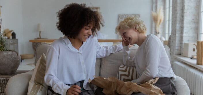 girlfriends laughing while chatting on sofa