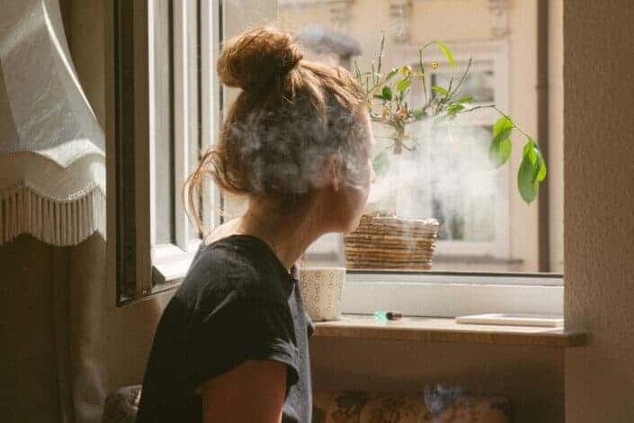 A woman looking outside while smoking her cigar