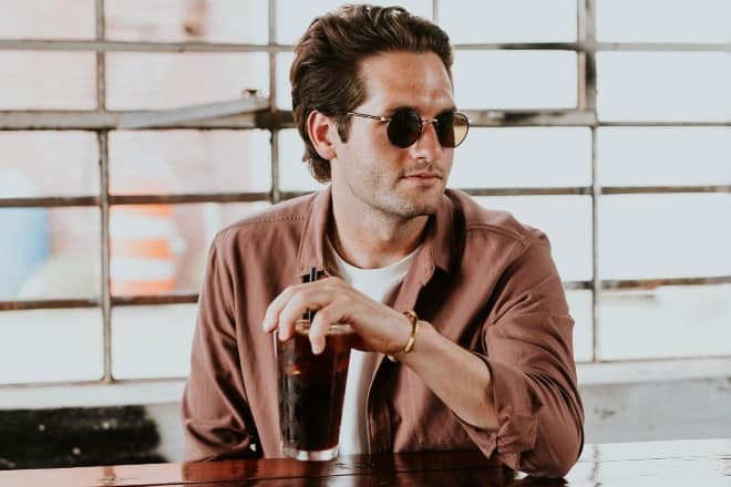 A gorgeous man drinking iced coffee in a counter - Things high value men never do