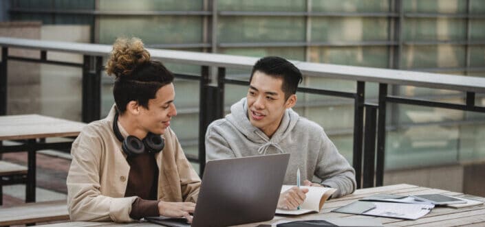 Two male friends discussing while researching