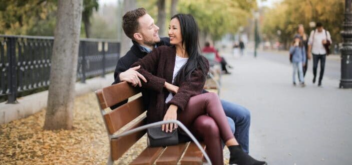 couple smiling while sitting on the bench