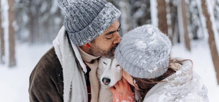 Couple hugging with their pet dog between them.