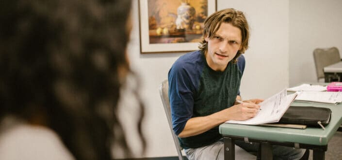 Man asking the woman beside his desk.