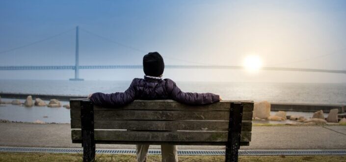 Man sitting on a bench watching the sunrise.