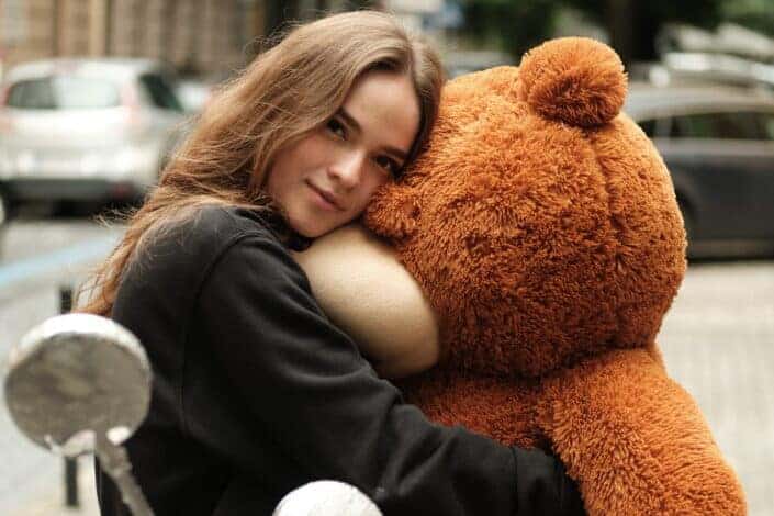 Woman hugging a life-sized teddy bear.