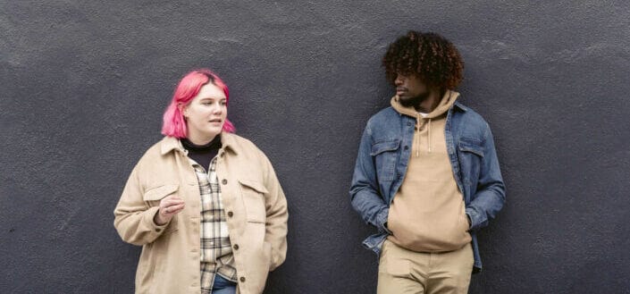 Diverse friends standing near gray wall