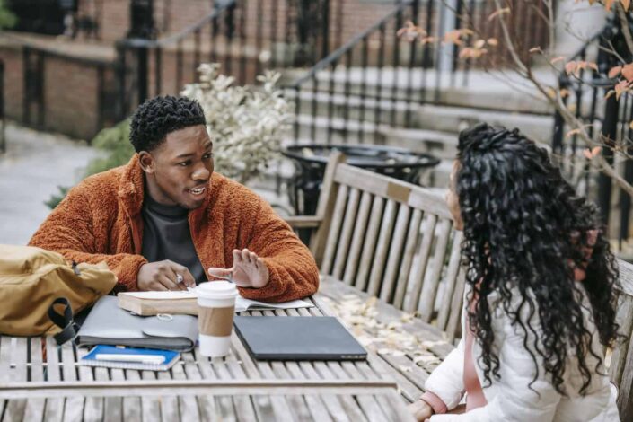 students discussing education at table with laptop