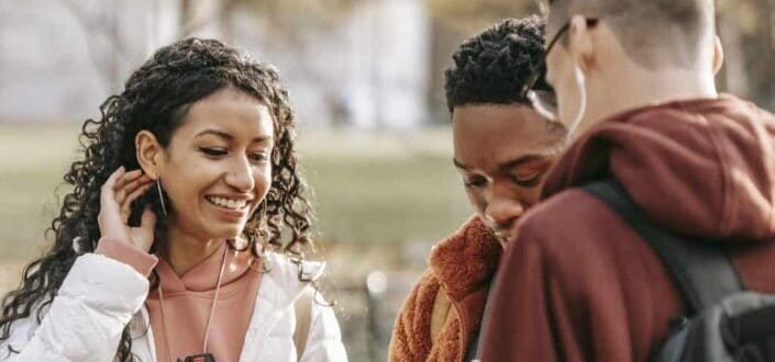 Multiethnic friends browsing smartphones in park