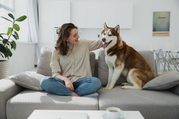 Woman sitting on couch with her husky