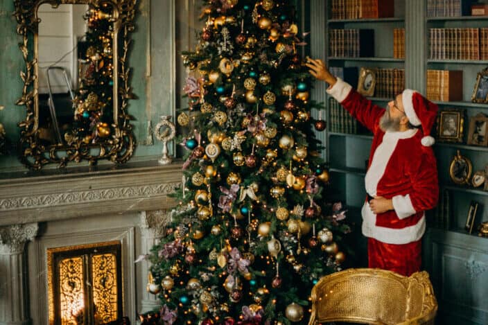 man wearing Santa's costume arranging his Christmas tree